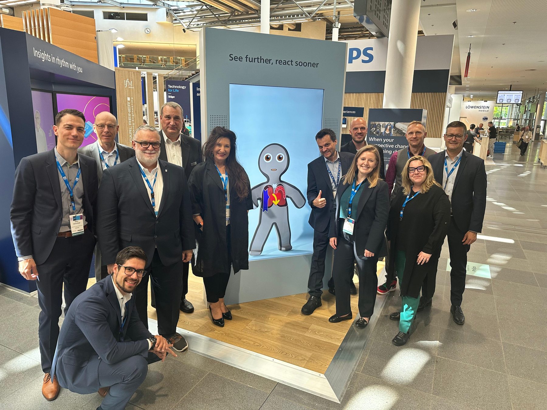 A group photograph beside the Visual Patient Avatar at Euroanaesthesia 2024 in Munich.
